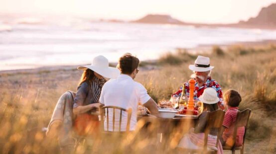 Family eating picnic dinner in sand dunes overlooking beach