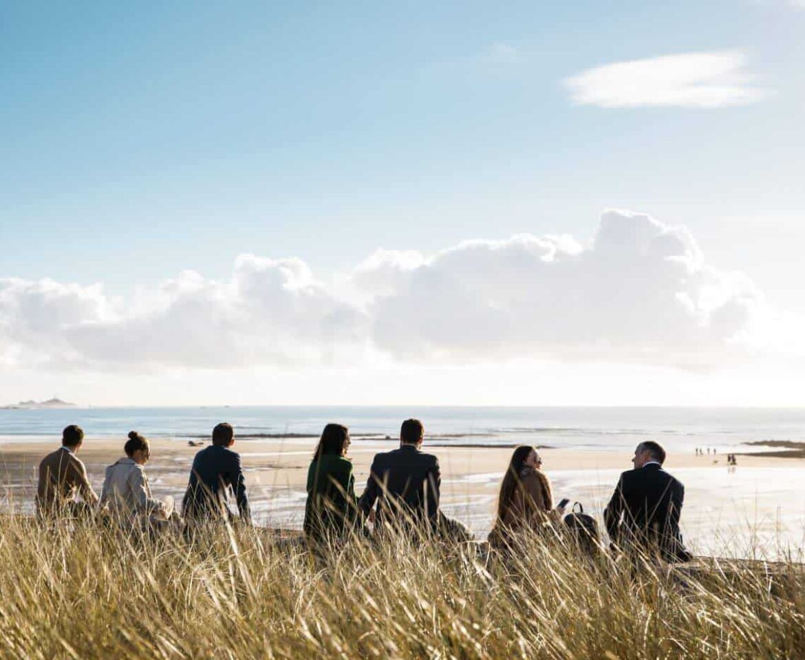 Group of people sat on the sea wall overlooking Saint Ouens bay
