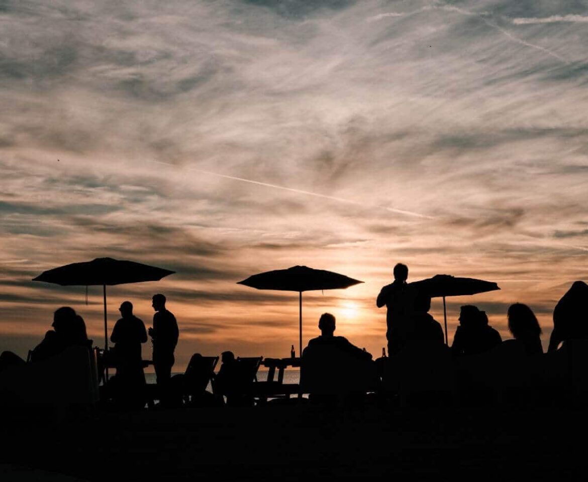 People dining al fresco silhouetted by the sunset