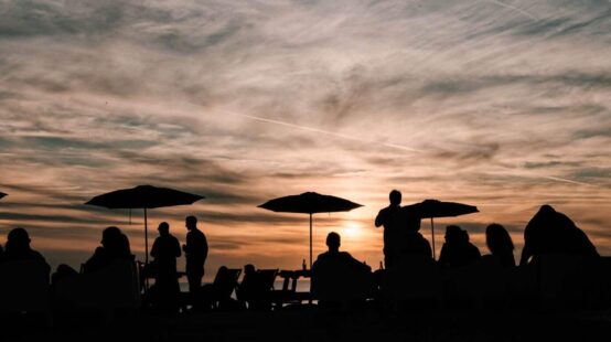 People dining al fresco silhouetted by the sunset