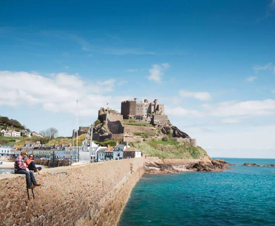 Two people sat on harbour wall in front of Gorey castle