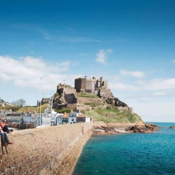 Two people sat on harbour wall in front of Gorey castle