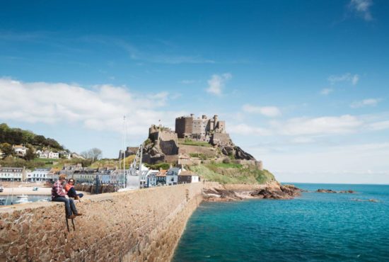 Two people sat on harbour wall in front of Gorey castle