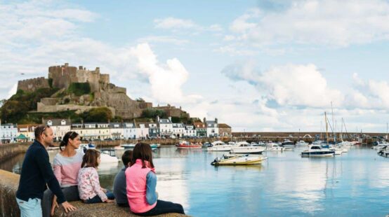 family sat on harbour well overlooking Gorey harbour with castle in background