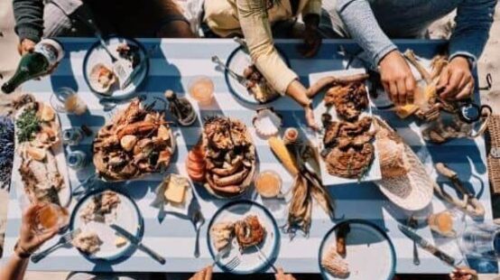 Aerial shot of group of people sat at a picnic table with feast