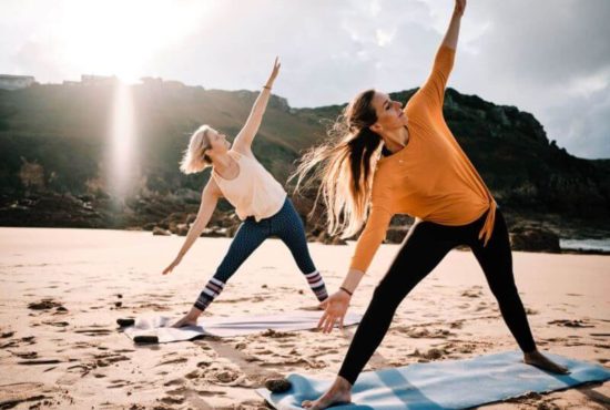 Two women doing yoga on the beach