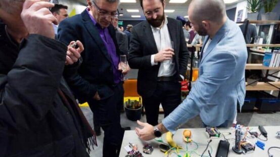 People chatting over a table of technology