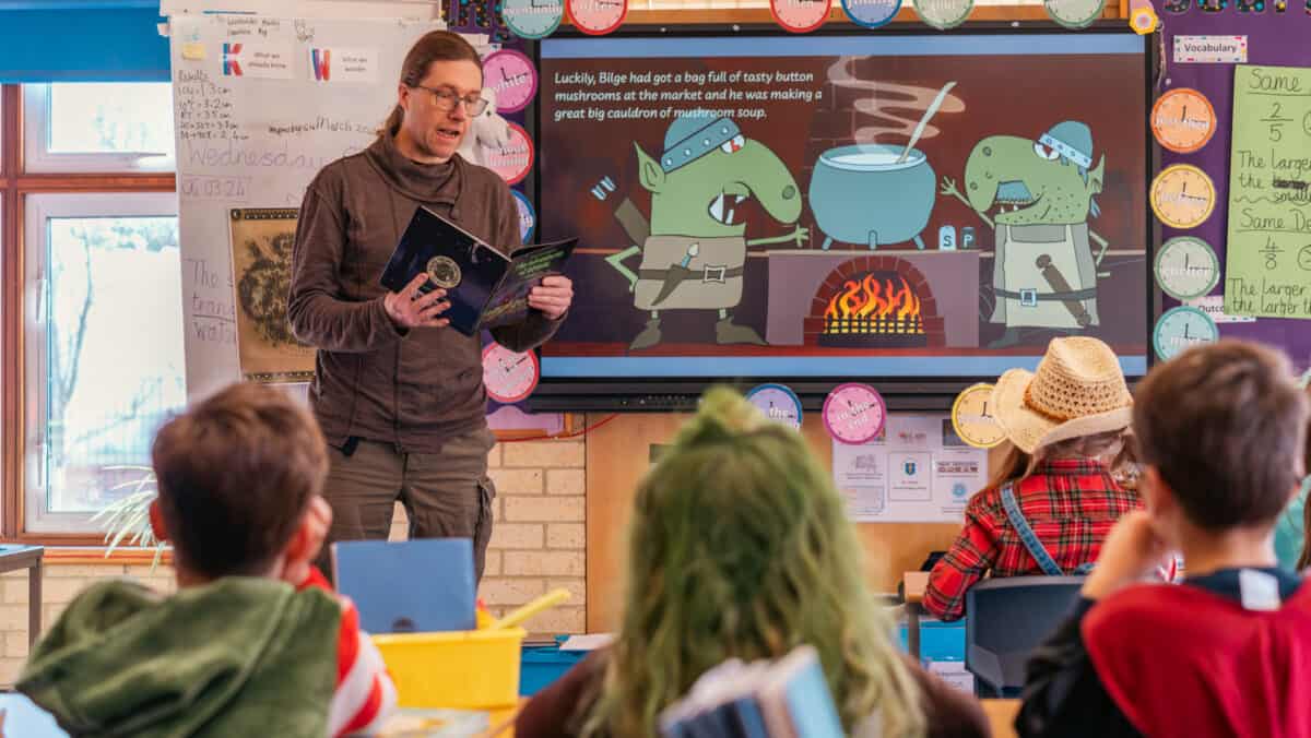  Noel Mallet, Senior Consultant at BDO|C5 Alliance reading his book to children in a classroom for World Book Day