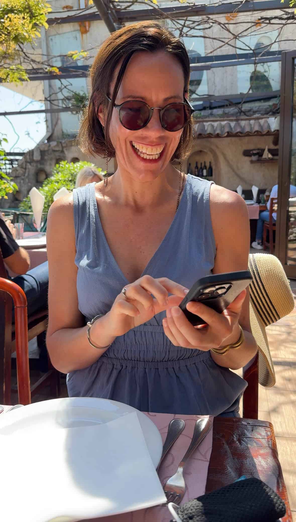 Woman smiling while using her phone to access the internet on holiday